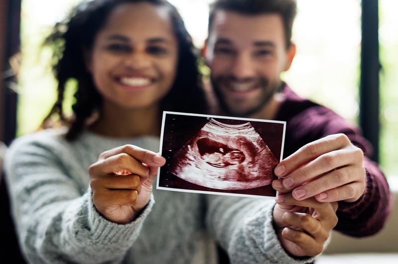 diverse couple smiling showing ultrasound