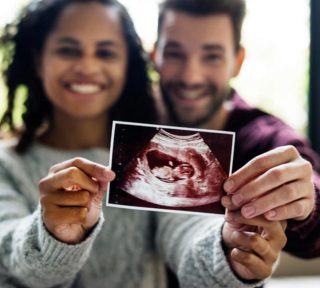 Interracial couple holding baby ultrasound image