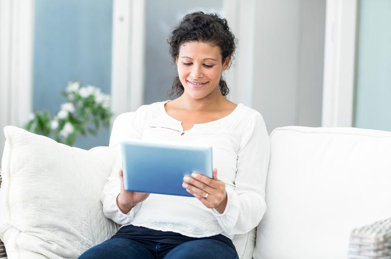 pregnant woman on tablet researching OB/GYN care