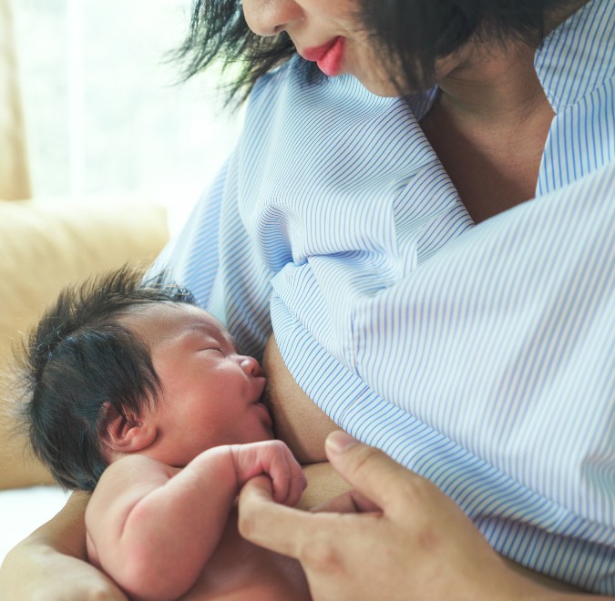 postpartum mother breastfeeding baby with fluffy hair